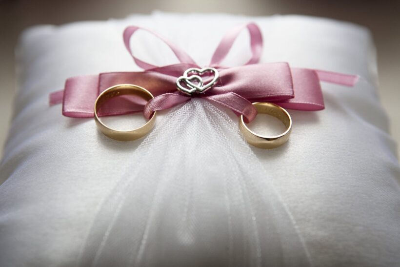 Selective Focus Photography of Silver-colored Engagement Ring Set With Pink Bow Accent on Throw Pillow